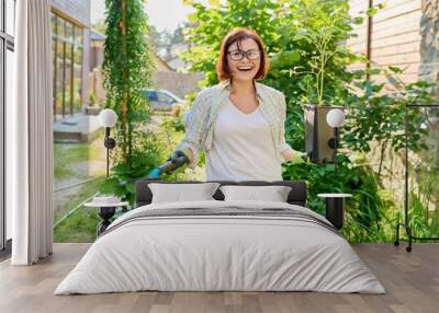 Smiling woman with flowerpot with peony plant and garden shovel Wall mural