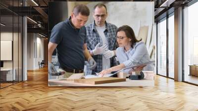 Team of carpenters workshop workers discussing a furniture project with client, designer, engineer. Wall mural