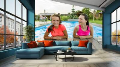 Two young teenage girls having fun in the swimming pool. Wall mural