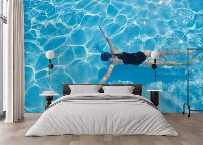 young woman swimming underwater in an outdoor pool, top view of back of girl Wall mural