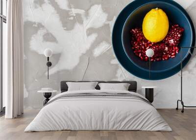 yellow lemon with red pomegranate seeds in a blue bowl on a blue plate Wall mural