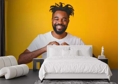 African American handsome man against yellow background smiling, expressing his feelings, showing love heart shape with hands, heart-shape sign Wall mural