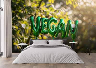 Word Vegan made from ballons floating in nature with tree leaves on background. Plant based green nutrition lifestyle. Vegetarian party in spring summer park Wall mural