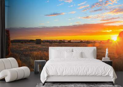 Panoramic view of hay bales on the field after harvesting illuminated by the last rays of setting sun Wall mural