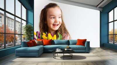 cute girl on a white background with bright flowers tulips. She smiles beautifully. Wall mural