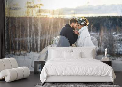 Beautiful couple sitting at a table at sunset. Winter evening. Wall mural