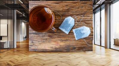 a cup of tea and two tea bags on a wooden table Wall mural