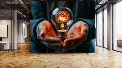 two hands holding a large light bulb. Inside the light bulb is an image of the brain glowing orange. Small glowing dots are visible around the brain, creating the effect of sparks. Wall mural