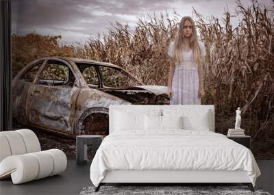 Ghost teen girl in white dress near a wrecked car. Holiday event halloween concept. Wall mural