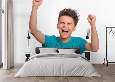 Portrait of successful teen boy winner with raised hands and clenching fists. Beautiful caucasian teenager shouting, isolated on white background. Happy cute child celebrating success with joy. Wall mural