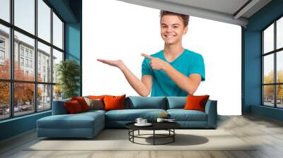 Portrait of teen boy pointing fingers away at copyspace, isolated on white background. Cute caucasian young teenager smiling and attracted by attention pointing fingers at something. Happy child. Wall mural