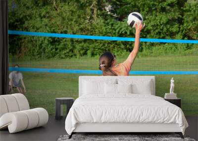 Girl serving volleyball on outdoor grass field Wall mural