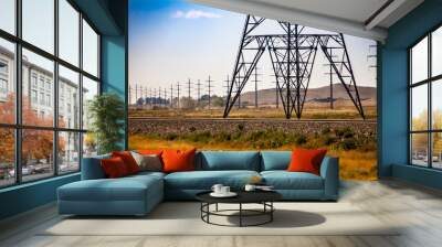 A wide angle view showing the base of a steel lattice electric pylon by a railroad with telegraph utility poles in rural Saskatchewan, Canada Wall mural