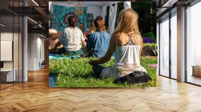 back view of blonde girl with a diverse group of people enjoying outdoor meditation session during a woodland spiritual gathering Wall mural