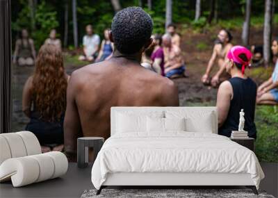 Diverse people enjoy spiritual gathering A multiethnic group of individuals are seen from the rear, kneeling on sacred ground in deep prayer during a retreat celebrating multicultural traditions. Wall mural