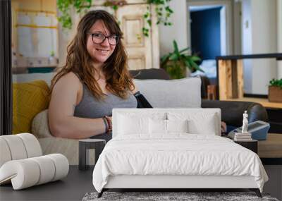 Happy portrait of a young woman in later stages of pregnancy carrying out routine health checks at home, wearing a blood pressure meter with arm cuff Wall mural