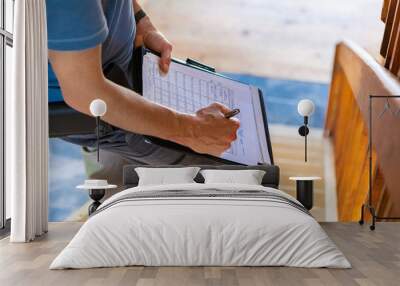 Indoor damp & air quality (IAQ) testing. A close up and high angle view of a professional male wearing blue t-shirt, writing out forms during a home inspection, standing on stairs with copy-space. Wall mural