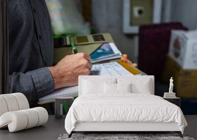 inspector holding a notebook in his hand during a home inspection in the basement, Close up and selective focus of a man taking professional notes. Wall mural