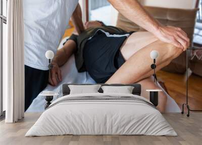 Medical massage of legs for a strong sportsman. A young man lying on the massage table and receiving treating leg massage Wall mural