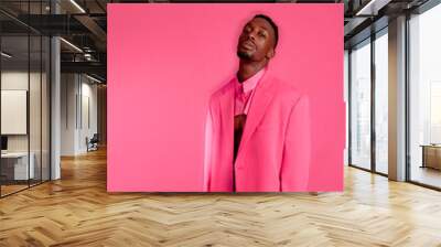 A fashionable black man. Fashion portrait of an African American male model. He wears pink suit on fuchsia background. Wall mural