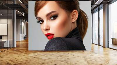 Beautiful girl with red lips and short hair. Pretty face of an young sensual woman. Closeup portrait of a model with bright makeup on a face. Attractive female posing at studio  in black closes. Wall mural