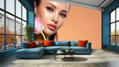 Beautiful white girl with flower. Stunning girl with  pink tulip. Closeup face of young woman with a healthy clean skin. Wall mural