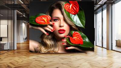 Beautiful white girl with red  flowers. Stunning girl with  Anthurium red. Closeup face of young beautiful blonde woman with a healthy clean skin. Pretty woman with bright makeup and long wavy hair. Wall mural