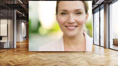 Close-up portrait of a smiling woman on the street. Happy woman's face closeup, outdoors. Happy businesswoman in a light jacket looks at the camera. Urban portrait of a beautiful blonde woman. Wall mural