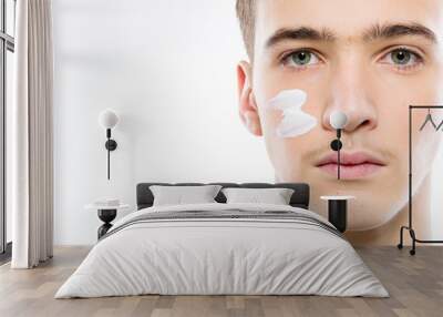 Close-up portrait of a young man with cosmetic cream on his face. Teenage guy cares about the cleanliness of the skin Wall mural