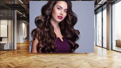 Face of a beautiful woman with long brown curly hair. Fashion model with wavy hairstyle. Attractive young  girl with curly hair posing at studio. Female face with purple makeup. Violet make-up. Wall mural