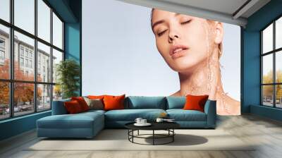 Photo of  young woman with clean skin and splash of water. Portrait of blonde woman with drops of water on her face. Spa treatment. Girl washing her body with water. Water and body. Wall mural