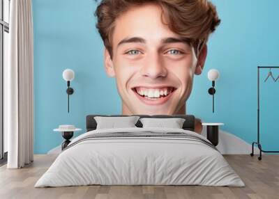 Portrait of a smiling young adult man with brown hair. Closeup face of a handsome young Caucasian man smiling at camera on a blue background. Front view, happy young European man in a white shirt. Wall mural