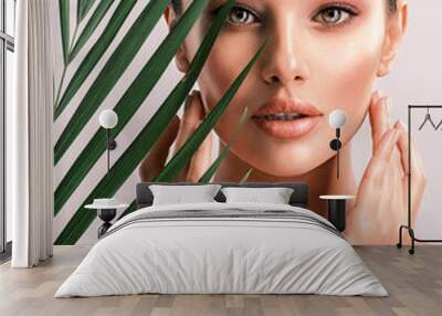 Young beautiful woman with green leaves near body. Skin care beauty treatments concept.  Closeup girl's face with green leaves. Wall mural