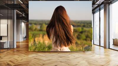 Young girl sits with his back to the camera and looks at nature Wall mural