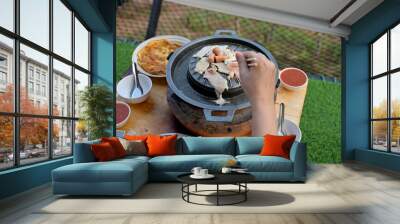 Right hand uses chopsticks to pick up pork, beef, seafood to be grilled in a  hot pan. Thai barbecue Grill Pork on hot pan buffet, It traditional Thai style BBQ, Set of food ready for grill on stove
 Wall mural