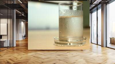 The clear glass of plain water with which the ice melted completely with water droplets attached to it. Place it on a wooden table in a conference room and have a blurred background.
 Wall mural