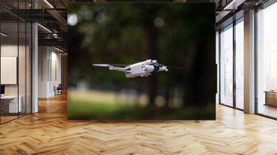 Vertical shallow focus shot of a white drone flying on a forest on bokeh background Wall mural