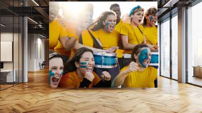 Crazy multiracial football fans celebrating in the crowd watching the game at sport stadium - Soccer supporters screaming for their team during championship event - Focus on right girl face Wall mural