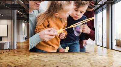 Gay male couple and kids having fun on the beach during summer vacation using soap bubble toy - Lgbt and love family concept - Main focus on right brother face Wall mural