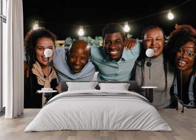 Happy African family having fun hugging together outdoors at night holiday house party - Celebration and relationship concept - Focus on left daughter face Wall mural