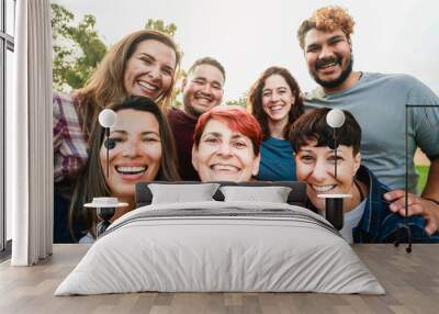 Multiracial friends with different age and ethnicity having fun taking self portrait at park city. Pov of group of people smiling on mobile phone camera Wall mural