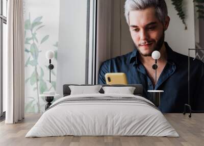 Young hipster man using smartphone indoors at home office - Focus on face Wall mural