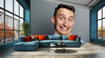 A man laughing hysterically at something hilarious with a funny expression on his face. Wall mural