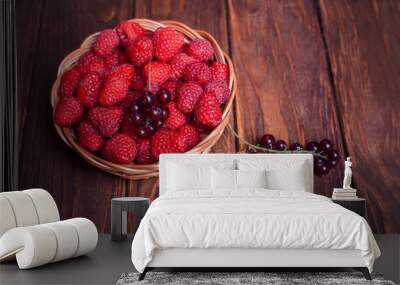 Red currant and raspberry in a basket on a wooden background Wall mural