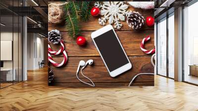 Smart phone mock up with headphones and rustic Christmas decorations for app presentation. View from above Wall mural