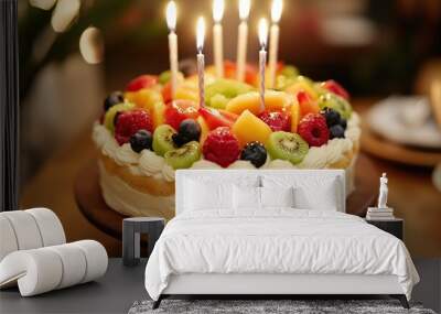 A cake with candles on top and fruit on the sides Wall mural