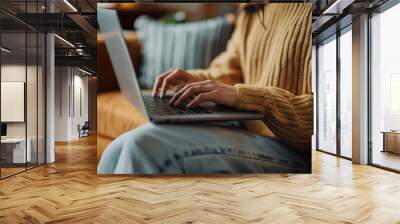 A woman is typing on a laptop while sitting on a couch Wall mural