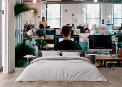 Open office area with rows of desks, computer monitors, and people working. The office is modern and collaborative, with a bright and productive atmosphere. Wall mural