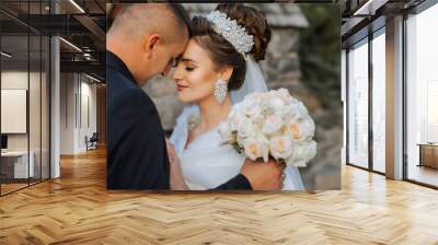 A bride and groom are embracing each other with a bouquet of white flowers in fr Wall mural