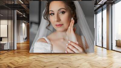 A bride is posing for a picture with her hands on her face. She is wearing a white dress and a veil Wall mural